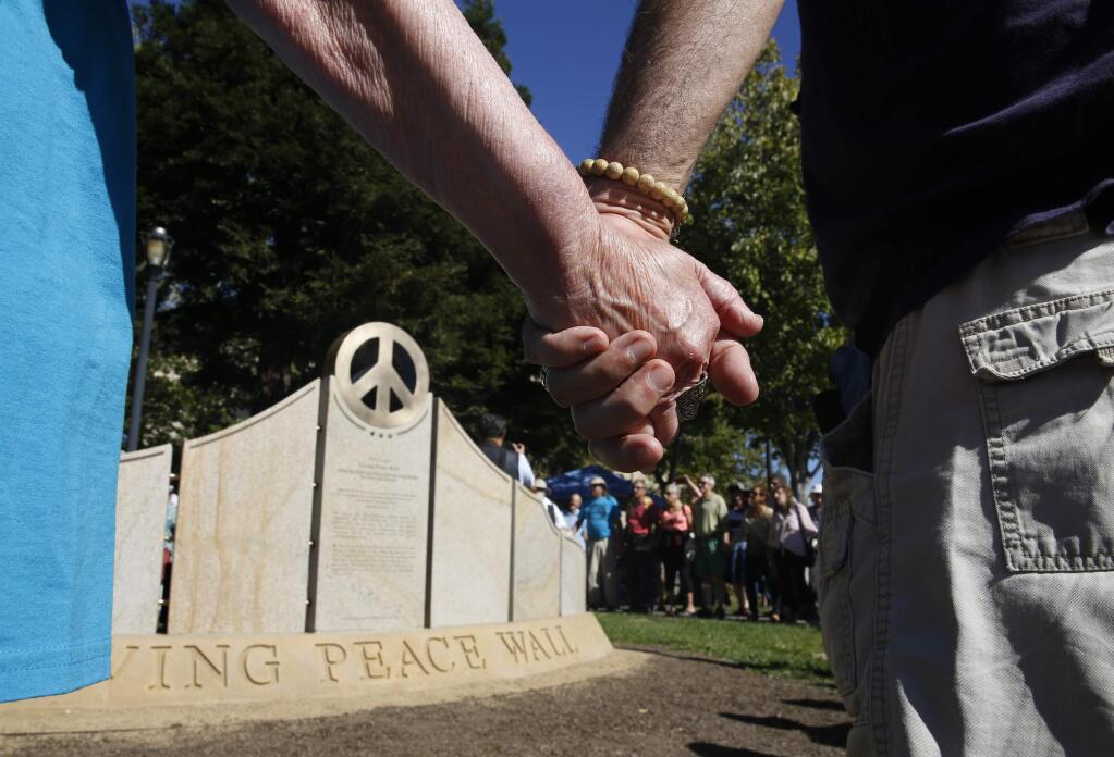 People gather and hold hands during the dedication of the Living Peace Wall on Sunday, Oct. 11, 2015 in Sebastopol. (BETH SCHLANKER / The Press Democrat)