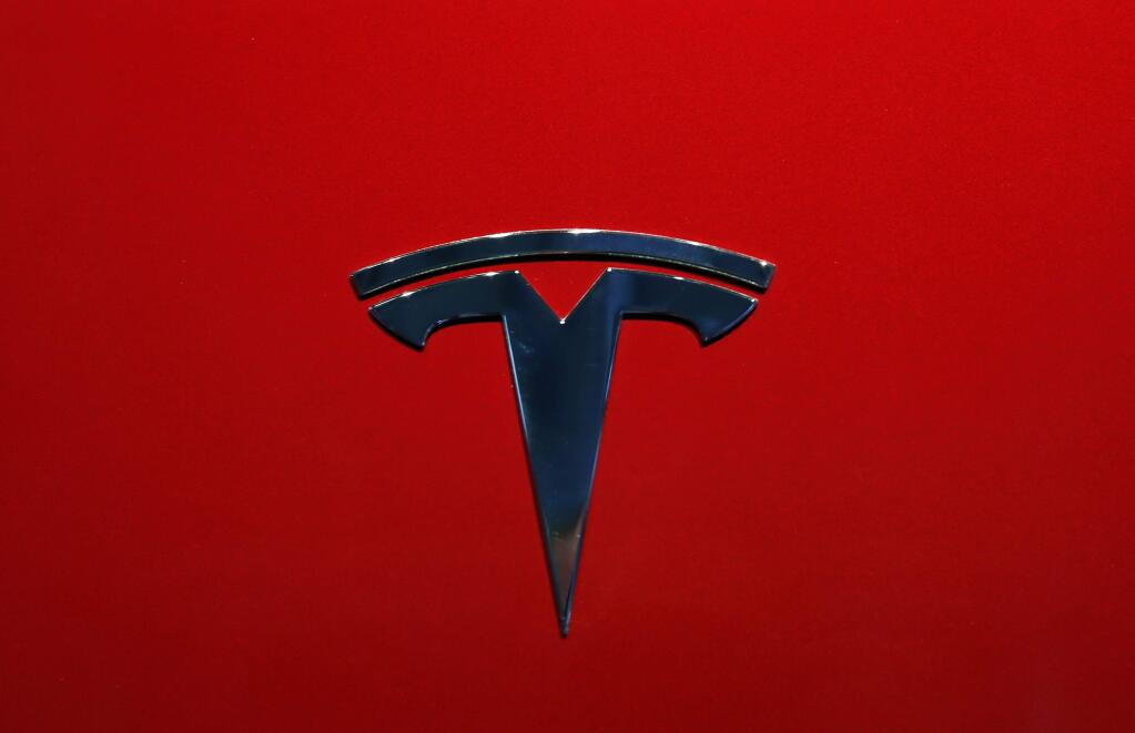 FILE - This Oct. 3, 2018, file photo shows the logo of Tesla Model 3 at the Auto show in Paris. The National Transportation Safety Board says two drivers, Tesla and lax regulation of new partially automated driving systems are to blame for a fatal 2019 crash in Florida involving a Tesla on Autopilot. The NTSB, in a report issued Thursday, March 19, 2020, said the design of the Autopilot system contributed to the crash because it allowed the Tesla driver to avoid paying attention. (AP Photo/Christophe Ena, File)