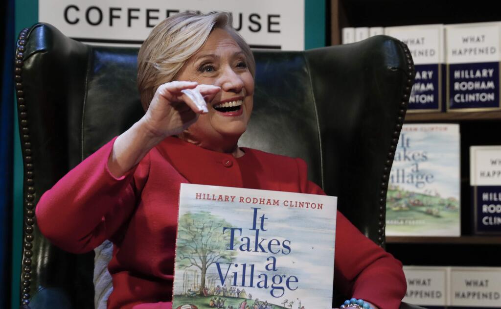 Hillary Clinton holds her book 'It Takes A Village' as she sits on stage at the Warner Theatre in Washington, Monday, Sept. 18, 2017, during a book tour event for her new book 'What Happened' hosted by the Politics and Prose Bookstore. (AP Photo/Carolyn Kaster)