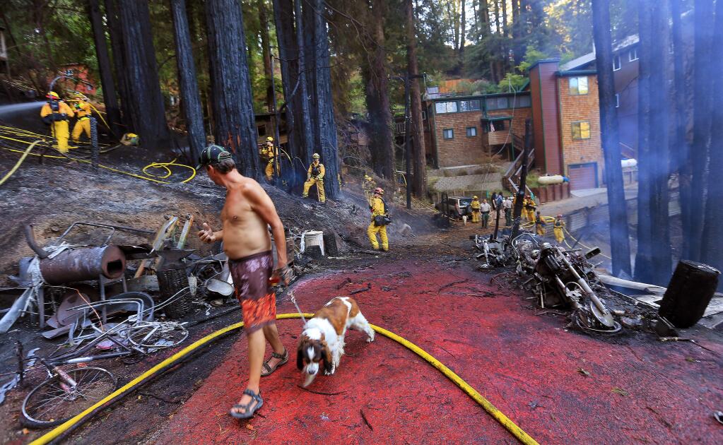 A resident walks through the fire area as Cal Fire firefighters and the Russian River Fire district douse hot spots on a large structure fire that threatened several homes in Forestville's Summerhome Park community, Monday Sept. 1, 2014. (KENT PORTER/ PD)