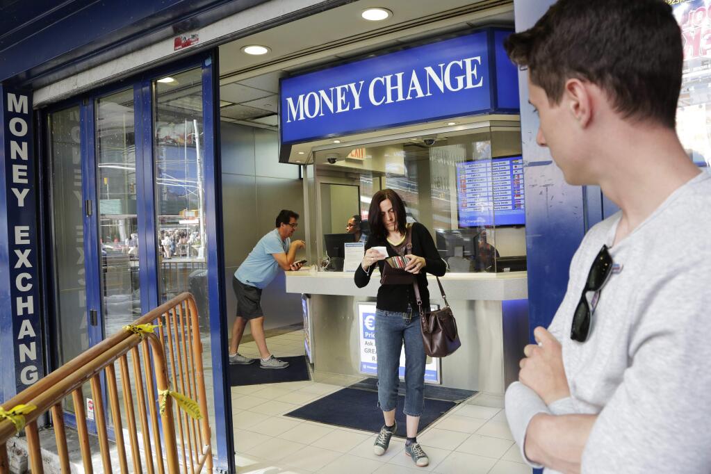 Claire Hunt, center, of Reading, England, changes pounds for dollars, Friday, June 24, 2016, at a money exchange in New York. Britain voted to leave the European Union after a bitterly divisive referendum campaign, toppling the government Friday, sending global markets plunging and shattering the stability of a project in continental unity designed half a century ago to prevent World War III. 'I think the exchange went down about eight percent (from yesterday),' said Hunt, who is vacationing with her son, Jacob Wood, right. 'It's scary. I don't know what we are going home to.' (AP Photo/Mark Lennihan)