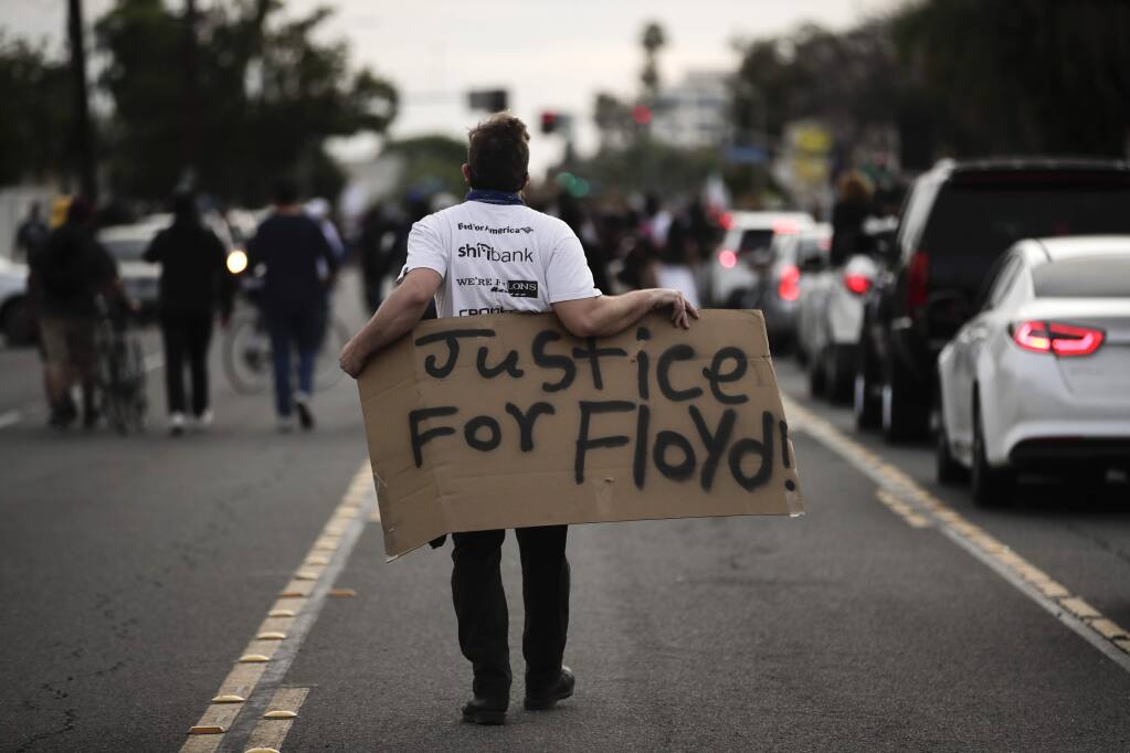 A demonstrator walks with a sign during a protest Monday, June 1, 2020, in Anaheim, Calif., over the death of George Floyd on May 25 in Minneapolis. (AP Photo/Jae C. Hong)