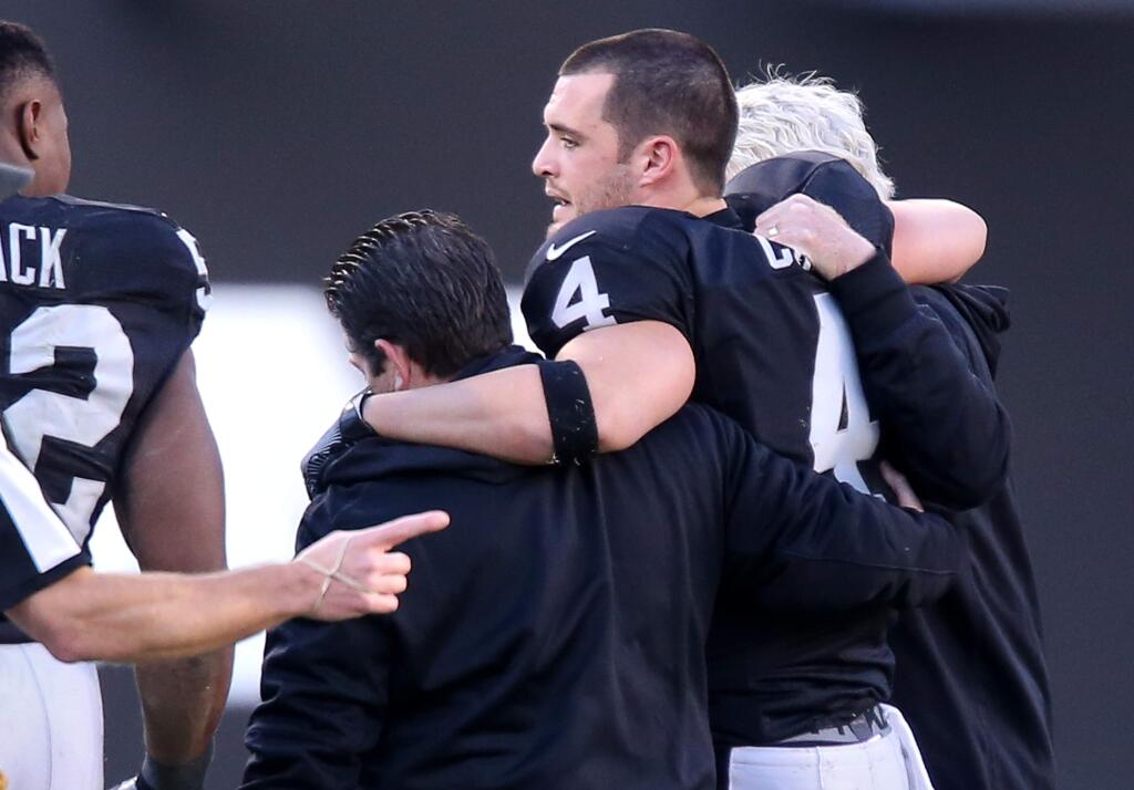 Oakland Raiders quarterback Derek Carr is helped off the field after being injured on a play against the Indianapolis Colts, during their game in Oakland on Saturday, December 24. The Raiders defeated the Colts 33-25. (Christopher Chung / The Press Democrat)