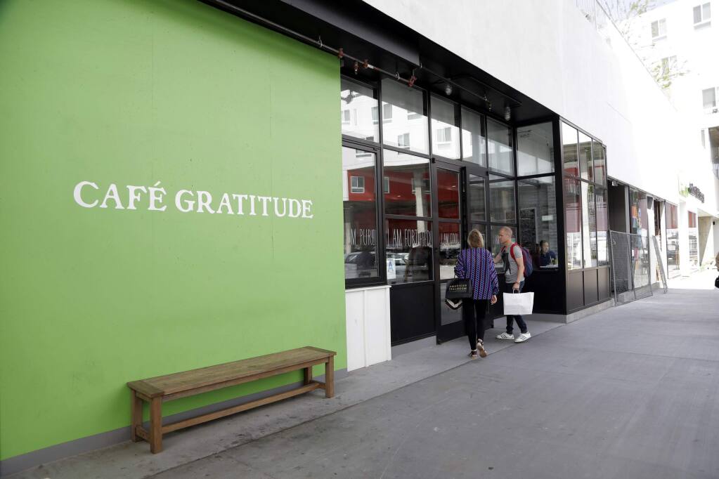 This Wednesday, May 4, 2016 photo shows Cafe Gratitude restaurant in Los Angeles. At the Cafe Gratitude restaurant chain in California, waiters serve plates of vegan rice bowls, vegetable pizzas and tempeh sandwiches with names like 'Gracious,' ''Warm-Hearted' and 'Magical.' Angry patrons and animal rights activists are calling on vegans to boycott the restaurant after learning that owners Matthew and Terces Engelhart have begun eating meat and consuming animals raised on their private farm. (AP Photo/Nick Ut)