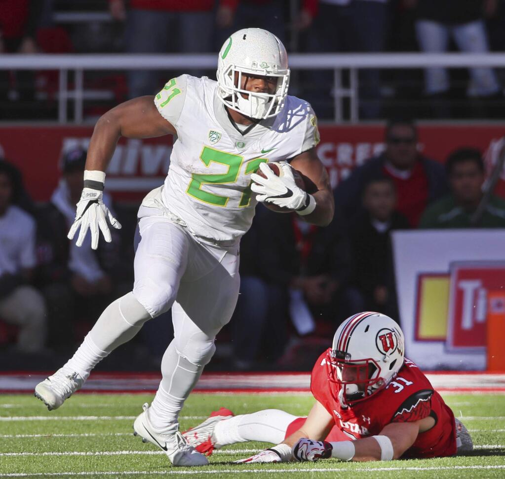 FILE - In this Nov. 19, 2016, file photo, Oregon running back Royce Freeman, left, runs past Utah linebacker Evan Eggiman in the second half of an NCAA college football game in Salt Lake City, Utah. Oregon running back Royce Freeman, USC quarterback Sam Darnold and UCLA quarterback Josh Rosen are among the Pac-12 players to keep an eye on coming out of spring practice. (AP Photo/George Frey, file)