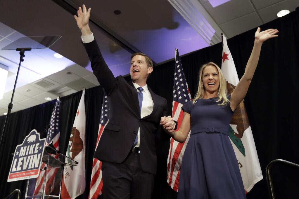 Democratic congressional candidate Mike Levin, left, waves on stage alongside his wife Chrissy, right, as he speaks to supporters Wednesday, Nov. 7, 2018, in Del Mar, Calif. Levin faces Republican candidate Diane Harkey in the race for California's 49th congressional district. (AP Photo/Gregory Bull)