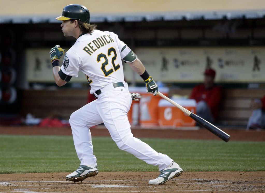 Oakland Athletics' Josh Reddick (22) drives in two runs with a single against the Los Angeles Angels during the first inning of a baseball game against the Los Angeles Angels Tuesday, April 28, 2015, in Oakland, Calif. (AP Photo/Marcio Jose Sanchez)