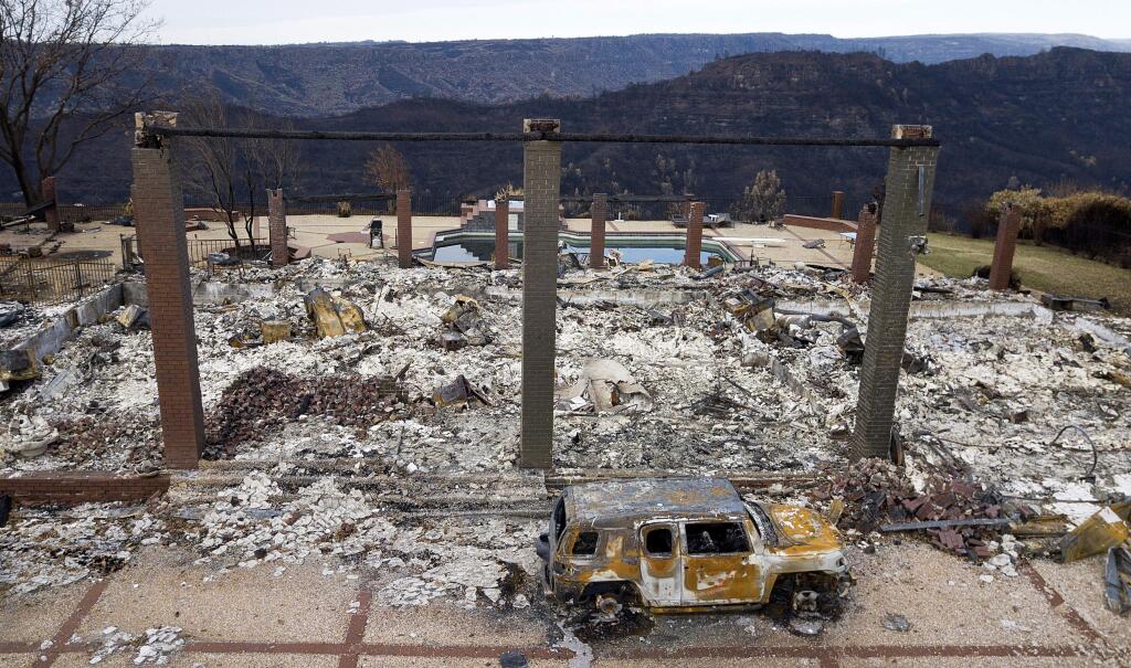 File - In this Dec. 3, 2018, file photo, a vehicle rests in front of a home leveled by the Camp Fire in Paradise, Calif. A federal judge on Tuesday, May 7, 2019, ordered board members of Pacific Gas & Electric to tour the Northern California town of Paradise, which was leveled by a wildfire that may have been caused by the utility's equipment. The judge ordered the tour as part of the utility's punishment for violating its felony probation terms, reported the San Francisco Chronicle. (AP Photo/Noah Berger, File)