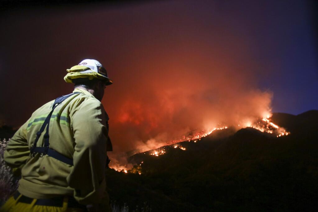 A firefighter watches a wildfire near Placenta Canyon Road in Santa Clarita, Calif., Sunday, July 24, 2016. Thousands of homes remained evacuated Sunday as two massive wildfires raged in tinder-dry California hills and canyons. (AP Photo/Ringo H.W. Chiu)