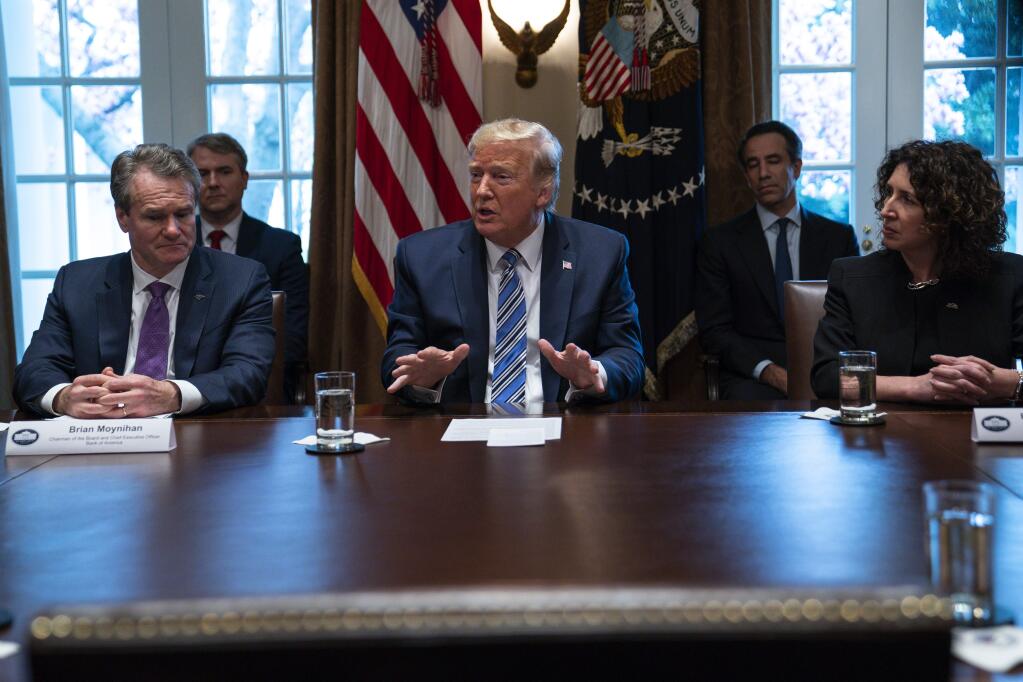 Bank of America CEO Brian Moynihan, left, and CEO of the Independent Community Bankers of America Rebeca Romero Rainey, right, listen as President Donald Trump speaks during a meeting with banking industry executives about the coronavirus, at the White House, Wednesday, March 11, 2020, in Washington. (AP Photo/Evan Vucci)