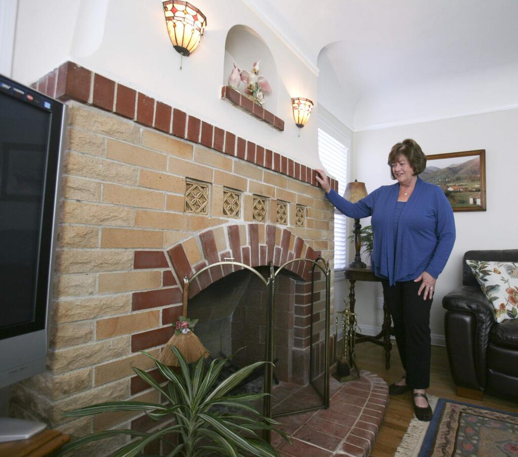 Realtor Kathy Schmidt with a wood burning fireplace that would have to be torn out or converted to gas if the house is sold in the future on Tuesday, May 12, 2015. (SCOTT MANCHESTER/ARGUS-COURIER STAFF)