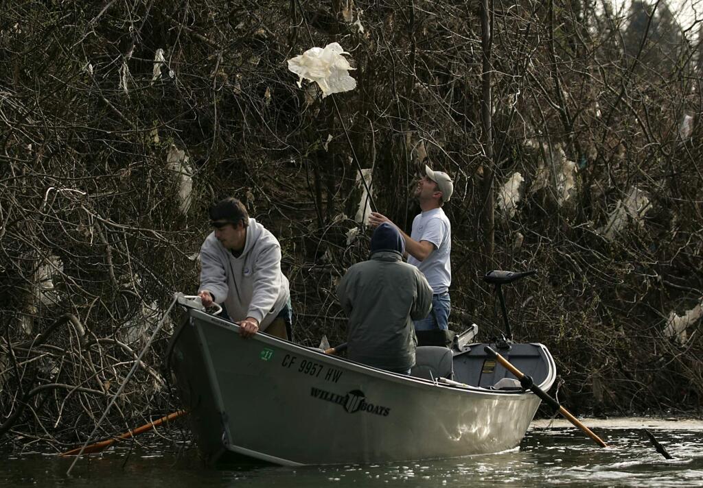 Nick Wheeler of Guerneville, picks off plastic sheeting as he helps to help clean up a dump site on the Russian River just east of Drakes Beach in Guerneville in 2011. (KENT PORTER/ PD FILE)