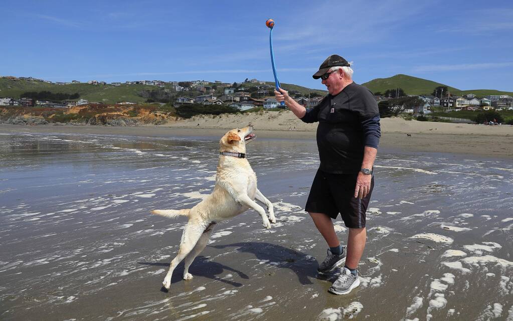 Dennis Rodgers plays with Roxy along Dillon Beach on Monday, April 9, 2018. Dillon Beach Resort, which includes the private beach, has been sold to new owners.(Christopher Chung/ The Press Democrat)