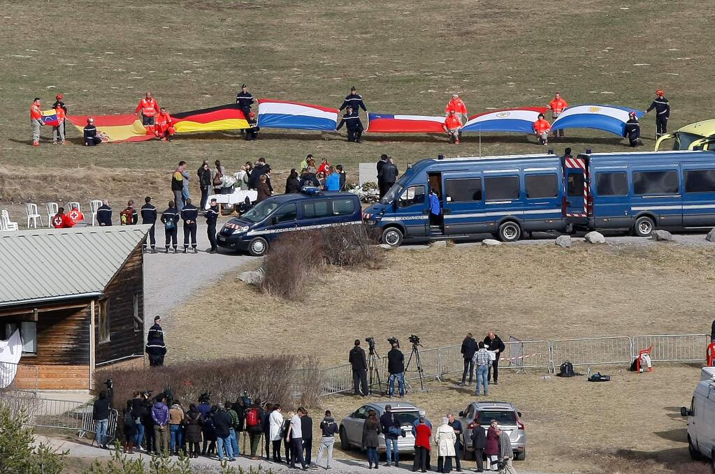 Flags representing differents nations are deployed during ceremony with family members of victims in front of a stele, a stone slab erected as a monument, set up in memory of the victims in the area where the Germanwings jetliner crashed in the French Alps, in Le Vernet, France, Sunday, March 29, 2015. The crash of Germanwings Flight 9525 into an Alpine mountain Tuesday killed all 150 people aboard, and has raised questions about the mental state of the co-pilot. Authorities believe the 27-year-old German deliberately sought to destroy the Airbus A320 as it flew from Barcelona to Duesseldorf. (AP Photo/Claude Paris)