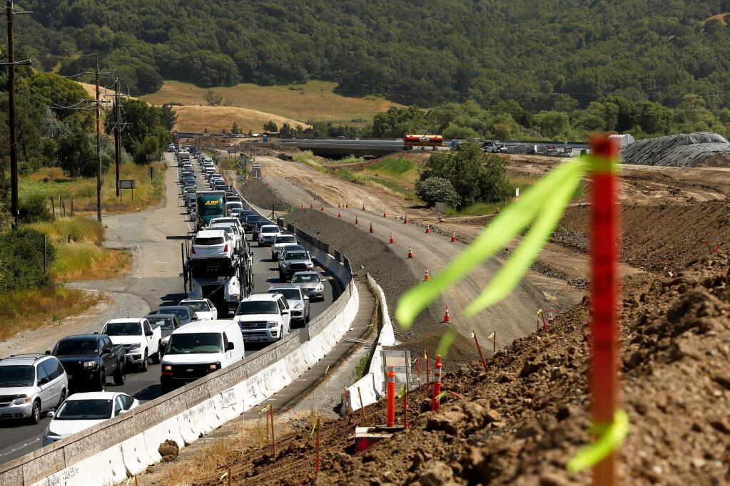 Motorists drive northbound in afternoon traffic on Highway 101, beside the road construction zone south of Petaluma, California, on Wednesday, May 30, 2018. The new bridge over San Antonio Creek is seen at center, in the background. (ALVIN JORNADA/THE PRESS DEMOCRAT)