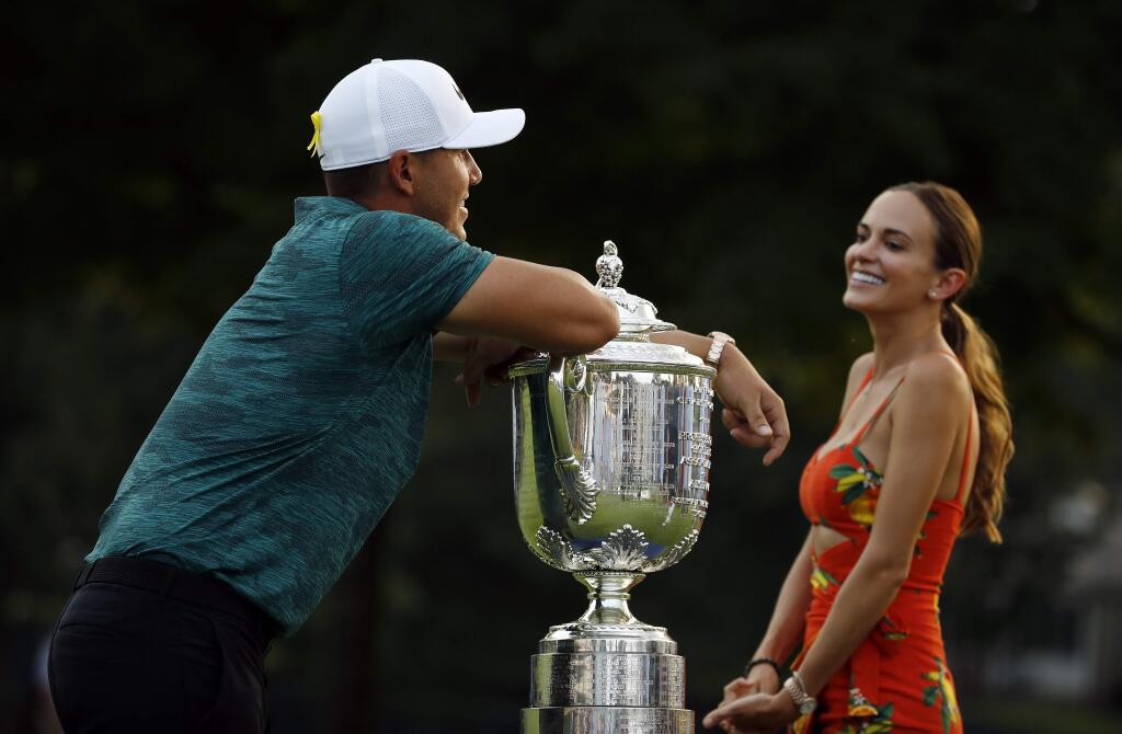 Brooks Koepka leans on the Wanamaker Trophy as he talks with his girlfriend, Jena Sims, after winning the PGA Championship golf tournament at Bellerive Country Club, Sunday, Aug. 12, 2018, in St. Louis. (AP Photo/Charlie Riedel)
