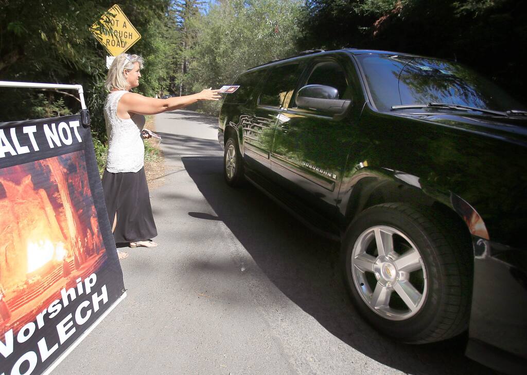 Christine Weick hands out literature at the entrance to the Bohemian Grove in Monte Rio Friday July 17, 2015 in Santa Rosa. (Kent Porter / Press Democrat) 2015