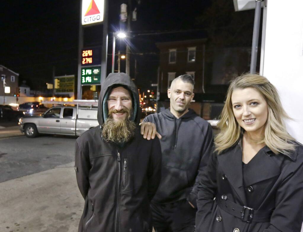 In this November 2017 photo, Johnny Bobbitt Jr., left, Kate McClure, right, and McClure's boyfriend, Mark D'Amico, pose at a Citgo station in Philadelphia. McClure and D'Amico, who raised more than $400,000 for Bobbitt Jr., a homeless man after he used his last $20 to fill up the gas tank of a stranded motorist in Philadelphia must now turn over what's left of the cash. (Elizabeth Robertson/The Philadelphia Inquirer)