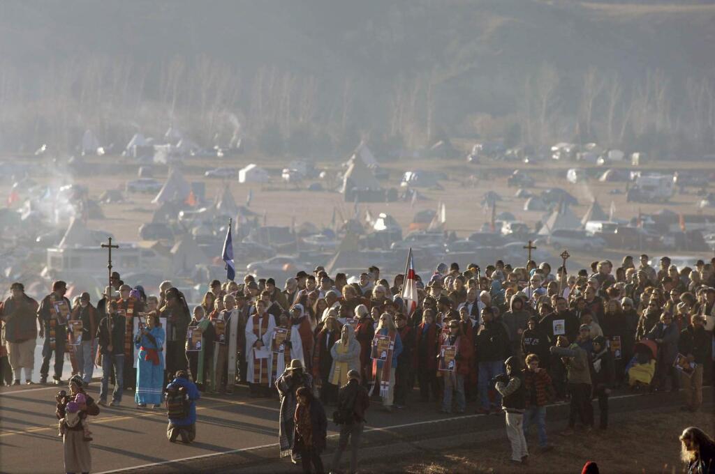 A long procession of hundreds clergy of numerous denominations and faiths walk on Highway 1806 from the Oceti Sakowin encampment to the site of the violent clash with law enforcement with Dakota Access Pipeline protesters, Thursday, Nov. 3, 2016 in Morton County, N.D. (Mike McCleary/The Bismarck Tribune via AP)