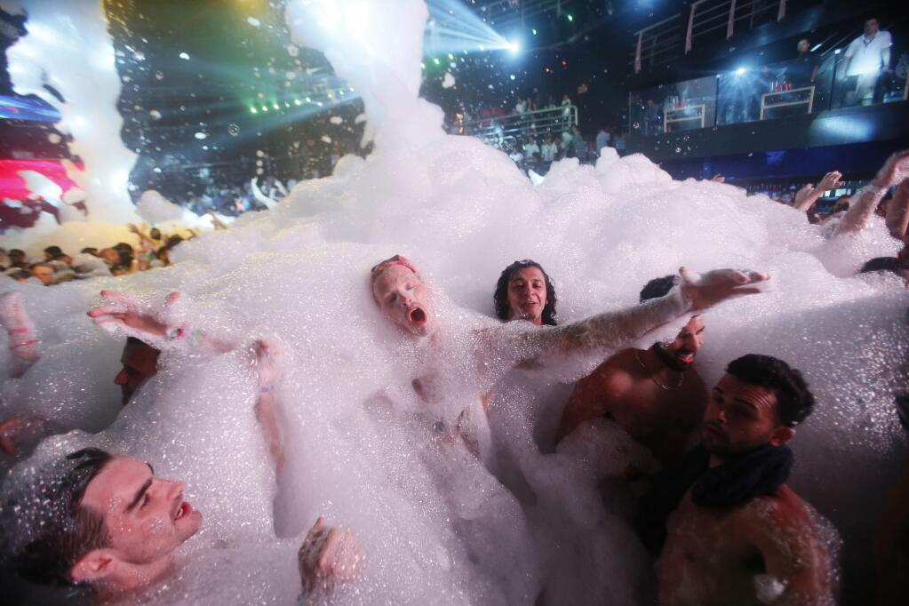 FILE - In this March 16, 2015 file photo, partygoers dance in foam at The City nightclub in the Caribbean resort city of Cancun, Mexico. Data so far this year is mixed on whether concerns about Zika are affecting spring break bookings for hotel stays and air travel to affected zones. (AP Photo/Israel Leal, File)
