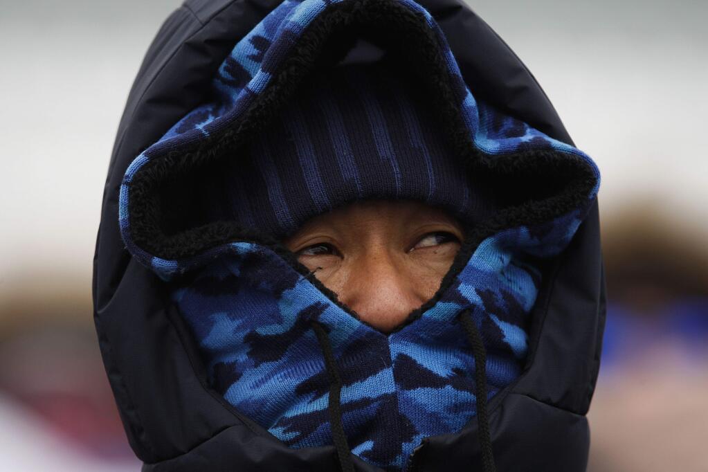 A spectator visiting from Japan waits for the start of the women's slopestyle qualifications at Phoenix Snow Park at the 2018 Winter Olympics in Pyeongchang, South Korea, Sunday, Feb. 11, 2018. The event was postponed due to weather conditions. (AP Photo/Jae C. Hong)