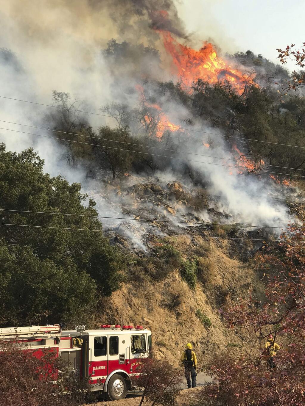 In this photo provided by the Santa Barbara County Fire Department, an engine company from the city of Colton, Calif., operating under mutual aid, keeps watch on pockets of burning and unburned vegetation off Bella Vista Dr. in Montecito, Calif., Wednesday, Dec. 13, 2017. After announcing increased containment on the Thomas fire, one of the biggest wildfires in California history, officials Wednesday warned that communities remain at risk and the threat could increase as unpredictable winds whip up again. (Mike Eliason/Santa Barbara County Fire Department via AP)