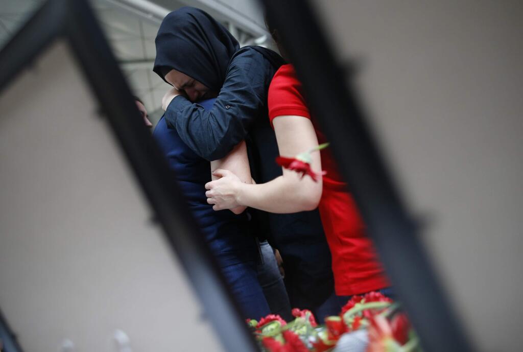 Two women embrace as family members, colleagues and friends of the victims of Tuesday blasts gather for a memorial ceremony at the Ataturk Airport in Istanbul, Thursday, June 30, 2016. A senior Turkish official on Thursday identified the Istanbul airport attackers as a Russian, Uzbek and Kyrgyz national hours after police carried out sweeping raids across the city looking for Islamic State suspects. Tuesday's gunfire and suicide bombing attack at Ataturk Airport killed dozens and injured over 200. Turkish authorities have banned distribution of images relating to the Ataturk airport attack within Turkey.(AP Photo/Emrah Gurel)