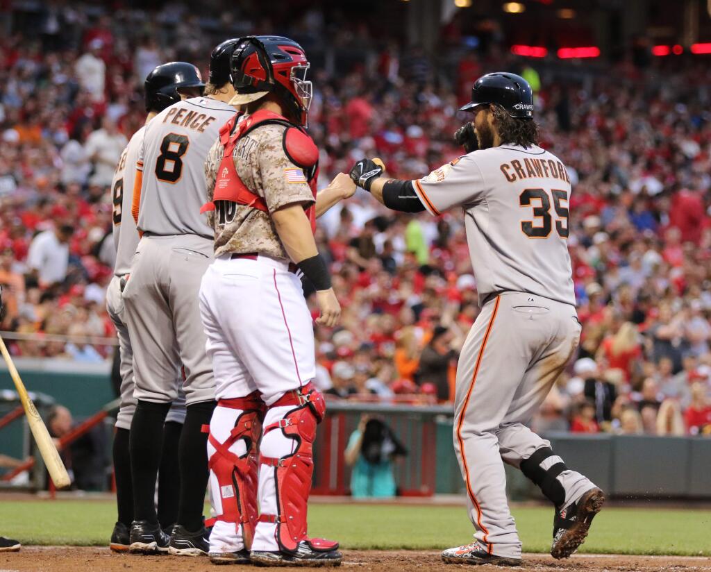 San Francisco Giants' Brandon Crawford (35) fists-bumps teammates after a grand slam off Cincinnati Reds starting pitcher Mike Leake during the fifth inning of a game Saturday, May 16, 2015, in Cincinnati. (AP Photo/Gary Landers)