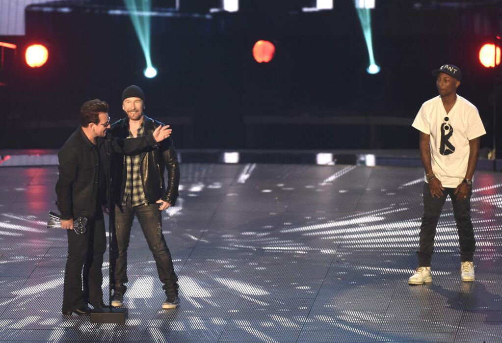 FILE - In a Sunday, April 3, 2016 file photo, Bono, left, and The Edge of U2 accept the innovator award as presenter Pharrell Williams looks on at right during the iHeartRadio Music Awards at The Forum, in Inglewood, Calif. U2, Drake, Britney Spears and Sting will perform at the 2016 iHearRadio Music Festival in September during the two-day event at the T-Mobile Arena in Las Vegas on Sept. 23-24, iHeartMedia announced Monday, July 25, 2016. (Photo by Chris Pizzello/Invision/AP, File)