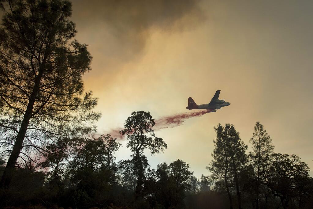 A plane drops retardant while battling a wildfire near Oroville, Calif., on Saturday, July 8, 2017. The fire south of Oroville was one of more than a dozen burning in the state as firefighters worked in scorching temperatures to control unruly flames. (AP Photo/Noah Berger)