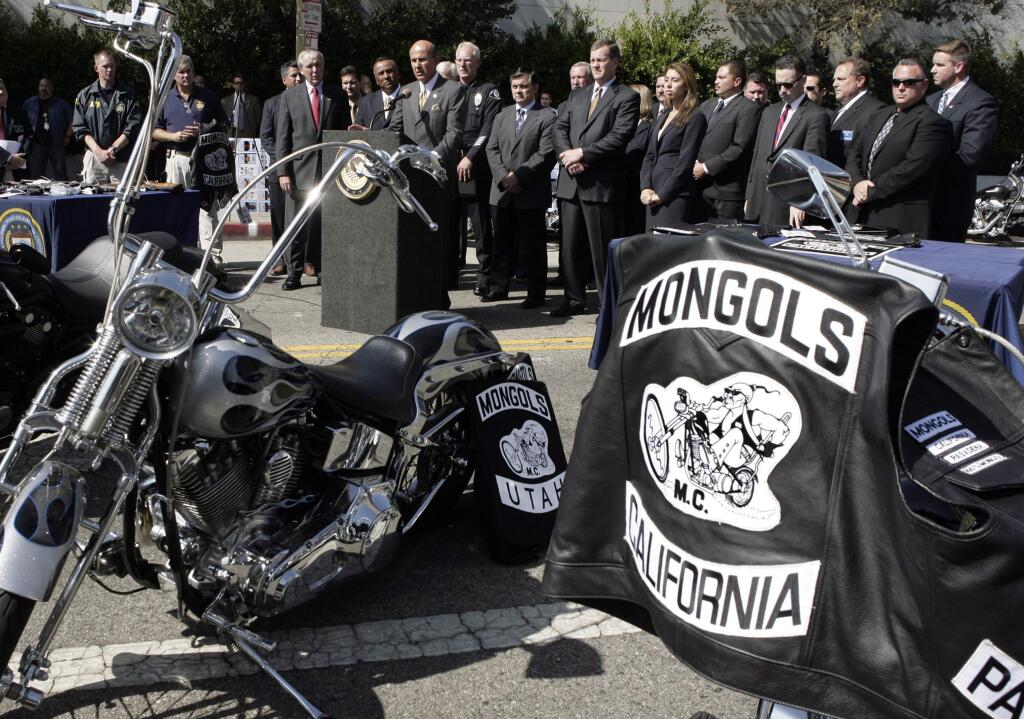 FILE - In this Oct. 21, 2008 file photo, Los Angeles County Sheriff Lee Baca, at podium, speaks during a news conference in Los Angeles with the trademarked Mongols logo seen on a motorcycle at right. A California federal judge has refused to order the Mongols motorcycle gang to forfeit its trademarked logo, delivering a blow to prosecutors. U.S. District Court Judge David O. Carter said Thursday, Feb. 28, 2019, that such an order would have been unconstitutional. (AP Photo/Ric Francis, File)