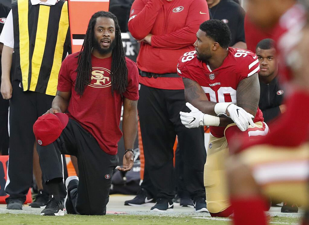 San Francisco 49ers defensive back Richard Sherman, left, watches from the sideline with defensive end DeForest Buckner during the first half of the team's preseason game against the Dallas Cowboys in Santa Clara, Thursday, Aug. 9, 2018. (AP Photo/Tony Avelar)