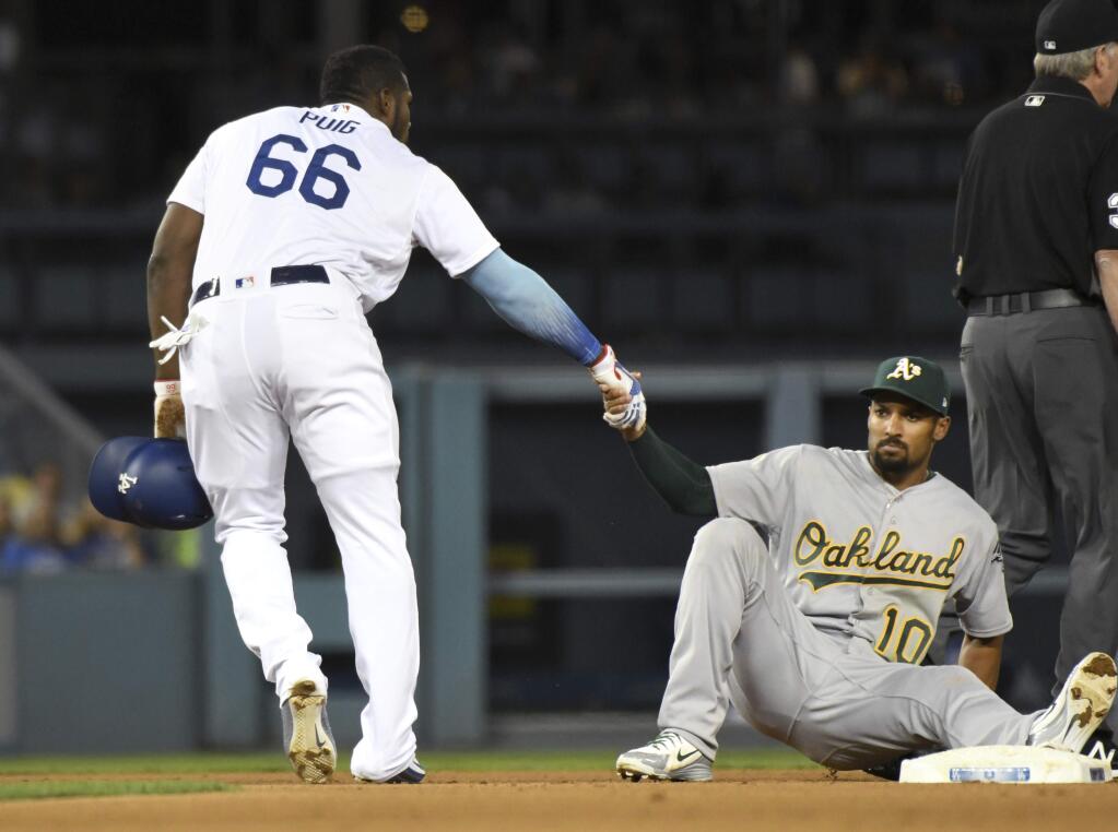 Los Angeles Dodgers' Yasiel Puig, left, helps up Oakland Athletics shortstop Marcus Semien after Semien tagged out Puig in the fifth inning of a baseball game Tuesday, April 10, 2018, in Los Angeles. (AP Photo/Michael Owen Baker)