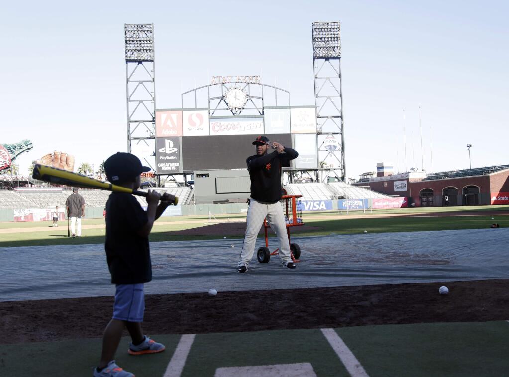 San Francisco Giants' Gregor Blanco, center, works on batting with son Gregor Jr., 4, after a team workout on Saturday, Oct. 18, 2014, in San Francisco. The Giants play the Kansas City Royals in Game 1 of baseball's World Series on Oct. 21 in Kansas City. (AP Photo/Marcio Jose Sanchez)