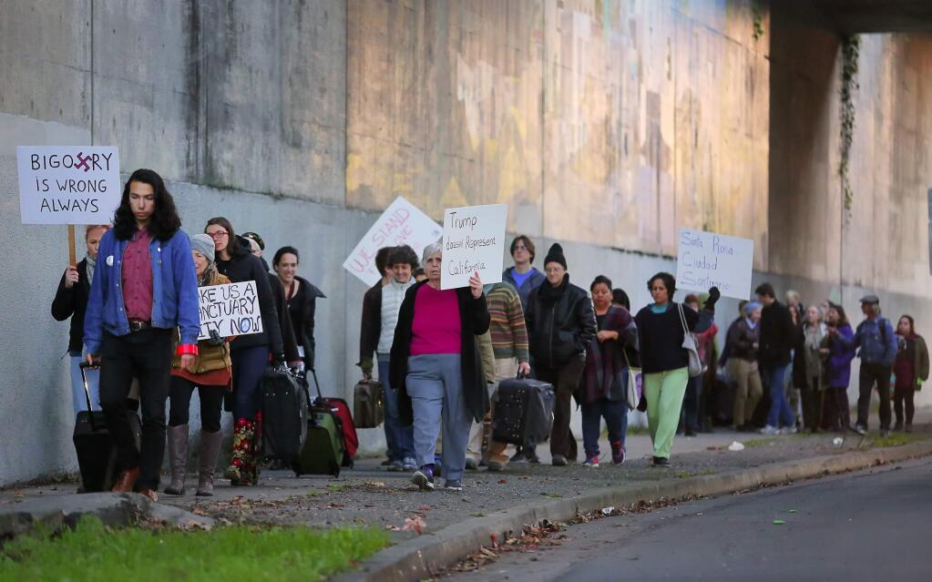 Activists in favor of making Santa Rosa a sanctuary city march with signs and suitcases, from Roseland Community Center to Santa Rosa City Hall, during an event organized by artist Maria de Los Angeles, on Thursday, December 22, 2016. (Christopher Chung/ The Press Democrat)