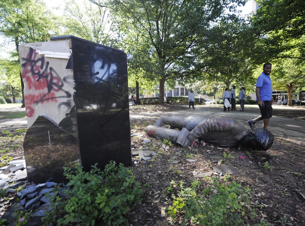 ADDS INFORMATION ON STATUE - An unidentified man walks past a toppled statue of Charles Linn, a city founder who was in the Confederate Navy, in Birmingham, Ala., on Monday, June 1, 2020, following a night of unrest. People shattered windows, set fires and damaged monuments in a downtown park after a protest against the death of George Floyd. Floyd died after being restrained by Minneapolis police officers on May 25. (AP Photo/Jay Reeves)