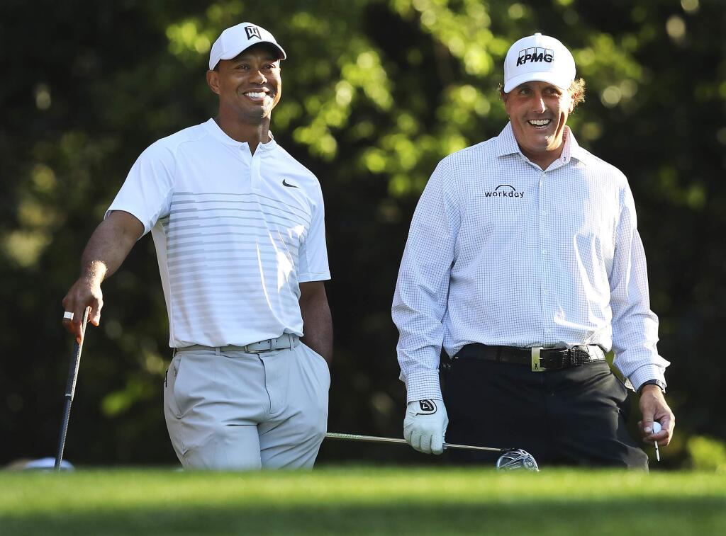 In this April 3, 2018, file photo, Tiger Woods, left, and Phil Mickelson share a laugh on the 11th tee box while playing a practice round for the Masters golf tournament at Augusta National Golf Club in Augusta, Ga. (Curtis Compton/Atlanta Journal-Constitution)
