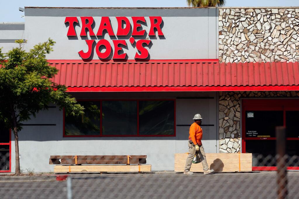 Brick layer Charles Toney walks past stacks of lumber staged in front of Trader Joe's on Cleveland Avenue, which is being refurbished after sustaining damage during the Tubbs Fire, in Santa Rosa, California, on Saturday, July 21, 2018. (Alvin Jornada / The Press Democrat)