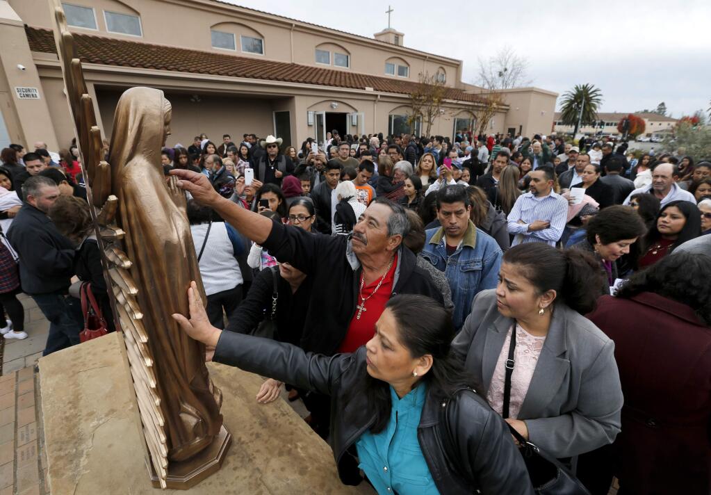 Parishioners pay their respects to a new statue of the Virgin of Guadalupe during the blessing and dedication of a new prayer garden at Our Lady of Guadalupe Catholic Church on Sunday, December 11, 2016 in Windsor, California . (BETH SCHLANKER/The Press Democrat)