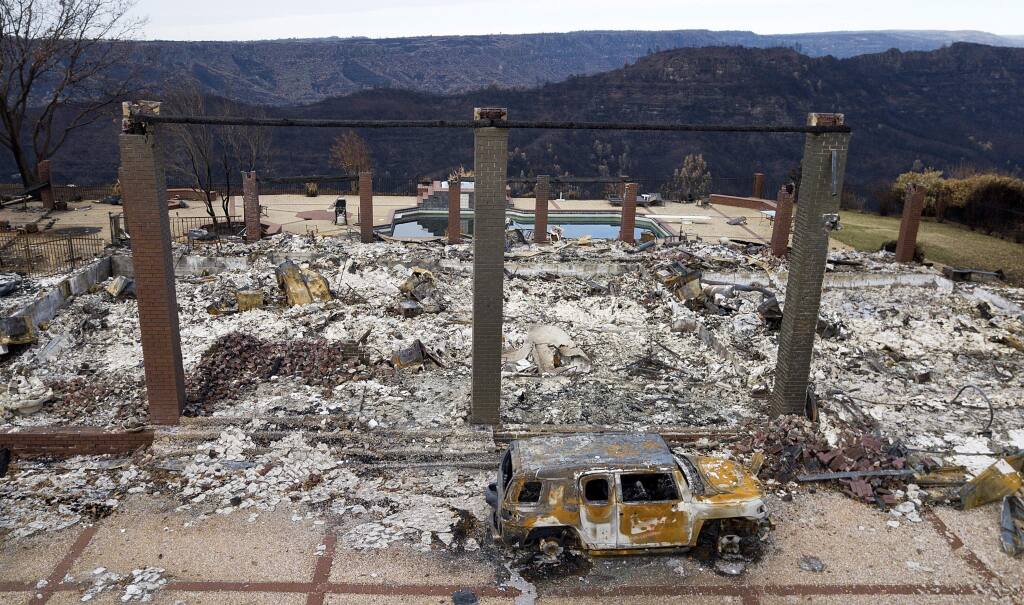 FILE - In this Dec. 3, 2018 file photo, a vehicle rests in front of a home leveled by the Camp Fire in Paradise, Calif. Pacific Gas & Electric says its equipment may have ignited the 2018 Camp Fire, which killed 86 people and destroyed an entire town in Northern California. The embattled utility said Thursday, Feb. 28, 2019, it's taking a $10.5 billion charge for claims connected to the Camp Fire in its fourth quarter earnings.(AP Photo/Noah Berger, File)