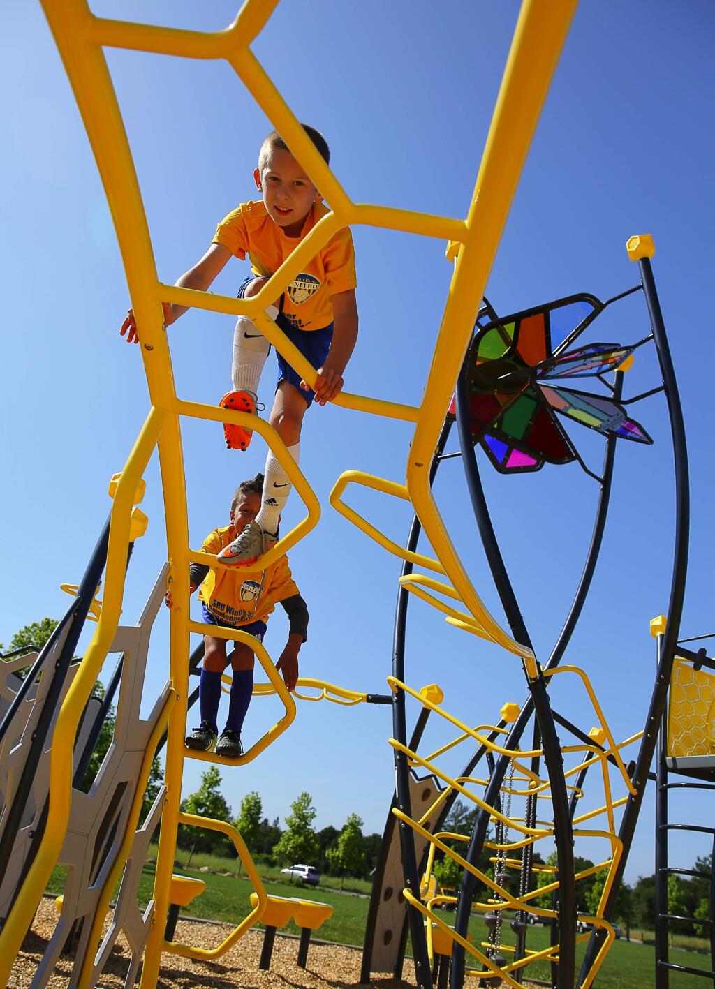 Cooper Gmitter, top, and Maximus Castillo, both 6, climb on top of the playground structure at A Place to Play park in Santa Rosa. (Christopher Chung/ The Press Democrat)