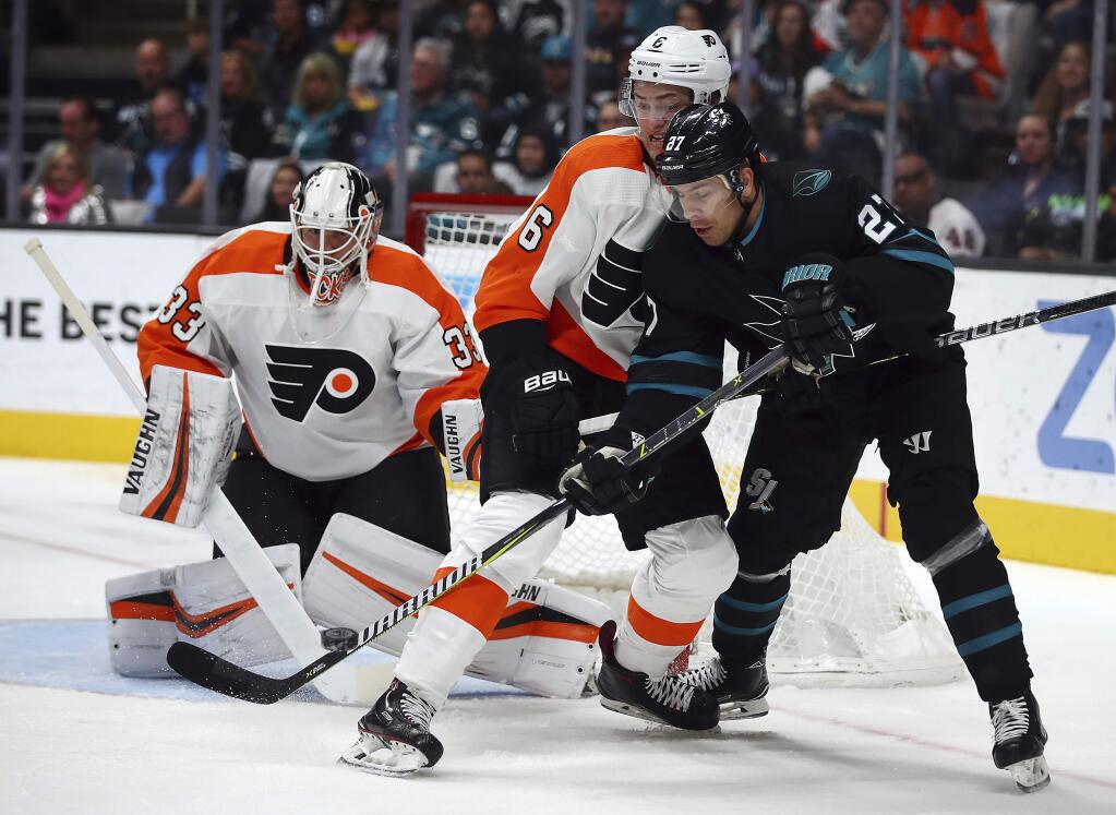 The San Jose Sharks' Joonas Donskoi, right, and the Philadelphia Flyers' Travis Sanheim fight for the puck in front of Flyers goalie Calvin Pickard during the first period Saturday, Nov. 3, 2018, in San Jose. (AP Photo/Ben Margot)