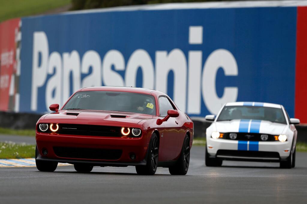 Kirk Larke, left, drives his Dodge Challenger around Turn 10 during Laps for Charity at Sonoma Raceway, in Sonoma, California on Saturday, January 21, 2017. (Alvin Jornada / The Press Democrat)