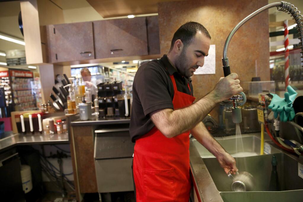Milad Ibrahim Al Najjar washes dishes between customers at Starbucks inside of Safeway on Tuesday, November 24, 2015 in Rohnert Park, California . (BETH SCHLANKER/ The Press Democrat)