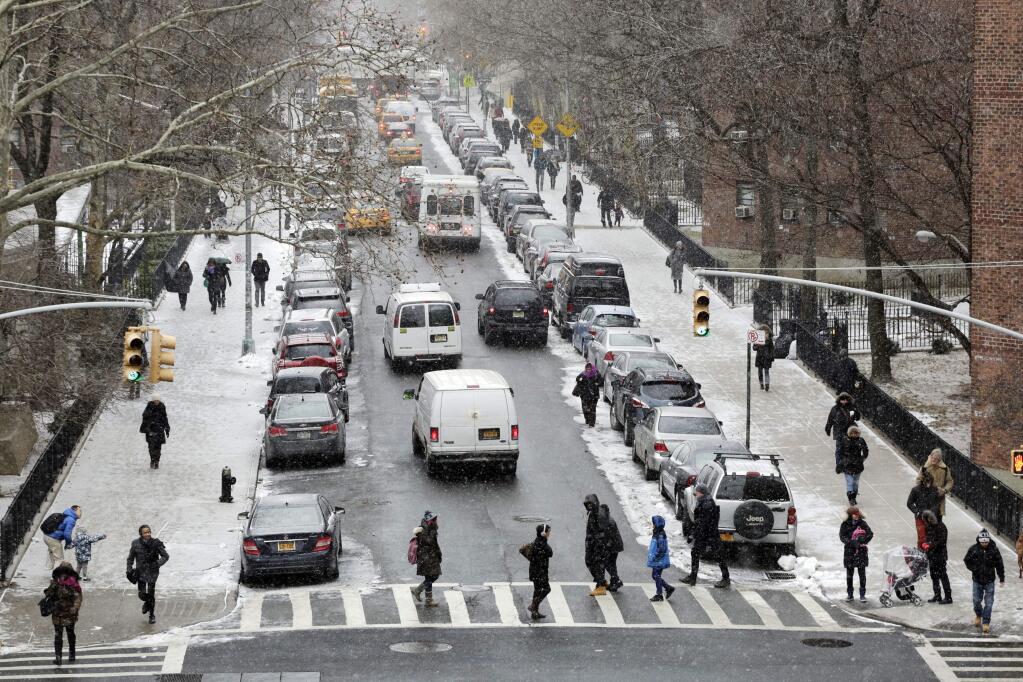 People walk in a light snowfall, Monday, Jan. 26, 2015 in New York. The National Weather Service says accumulations of 18 to 24 inches are possible by Tuesday afternoon. (AP Photo/Mark Lennihan)
