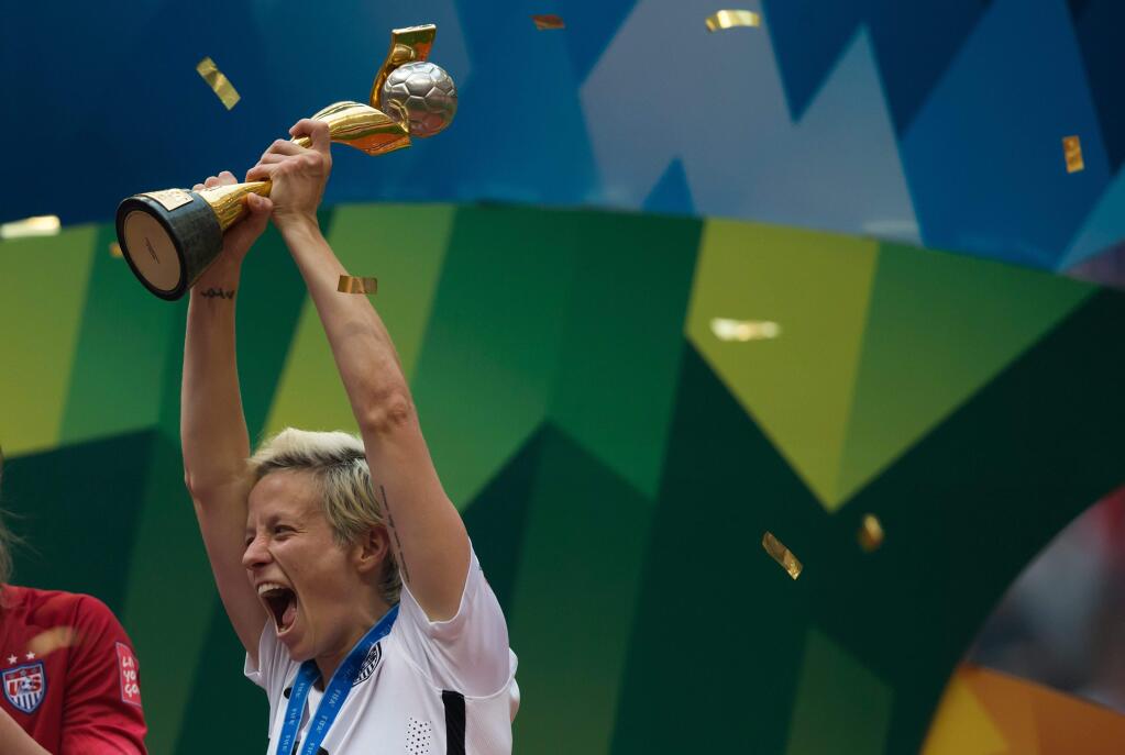 United States' Megan Rapinoe hoists the trophy as she celebrates after defeating Japan to win the FIFA Women's World Cup soccer championship in Vancouver, British Columbia, Canada, Sunday, July 5, 2015. (Darryl Dyck/The Canadian Press via AP) MANDATORY CREDIT