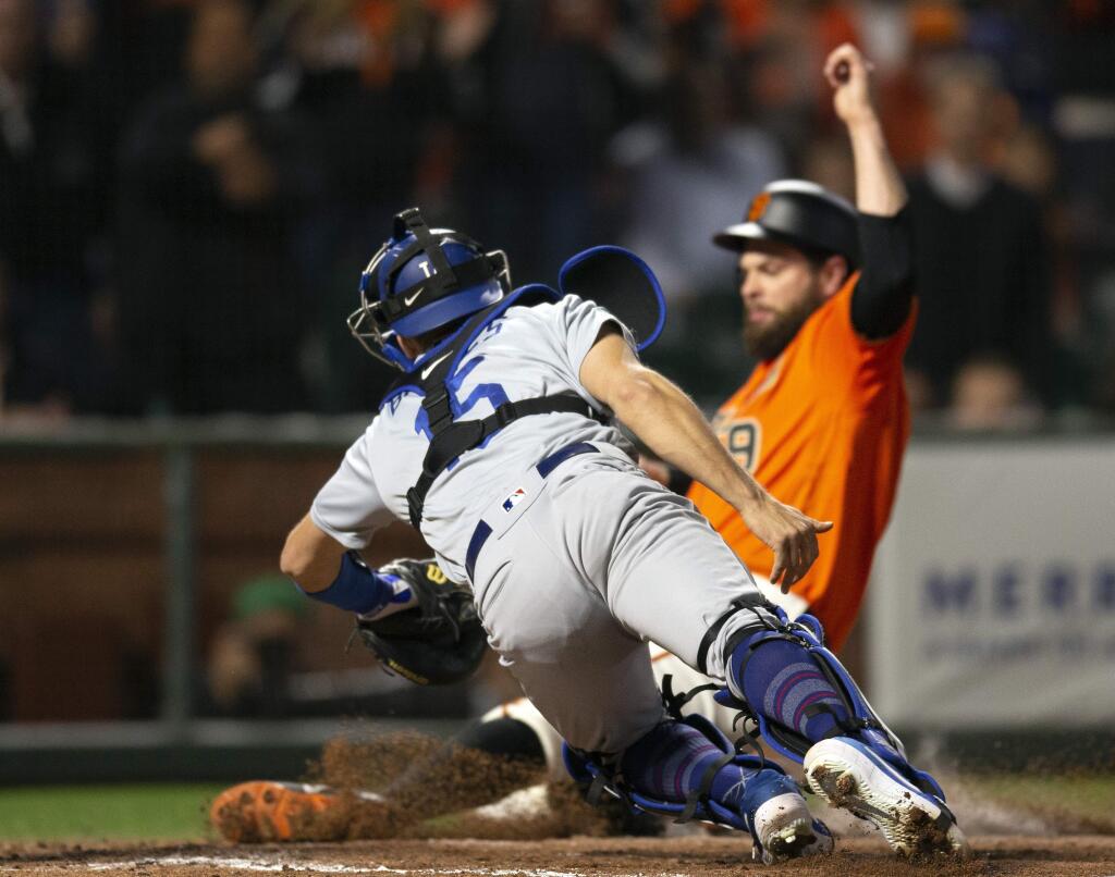Los Angeles Dodgers catcher Austin Barnes dives too late to tag out the San Francisco Giants' Brandon Belt, who scored from second on a single by Kevin Pillar during the sixth inning Friday, June 7, 2019, in San Francisco. (AP Photo/D. Ross Cameron)