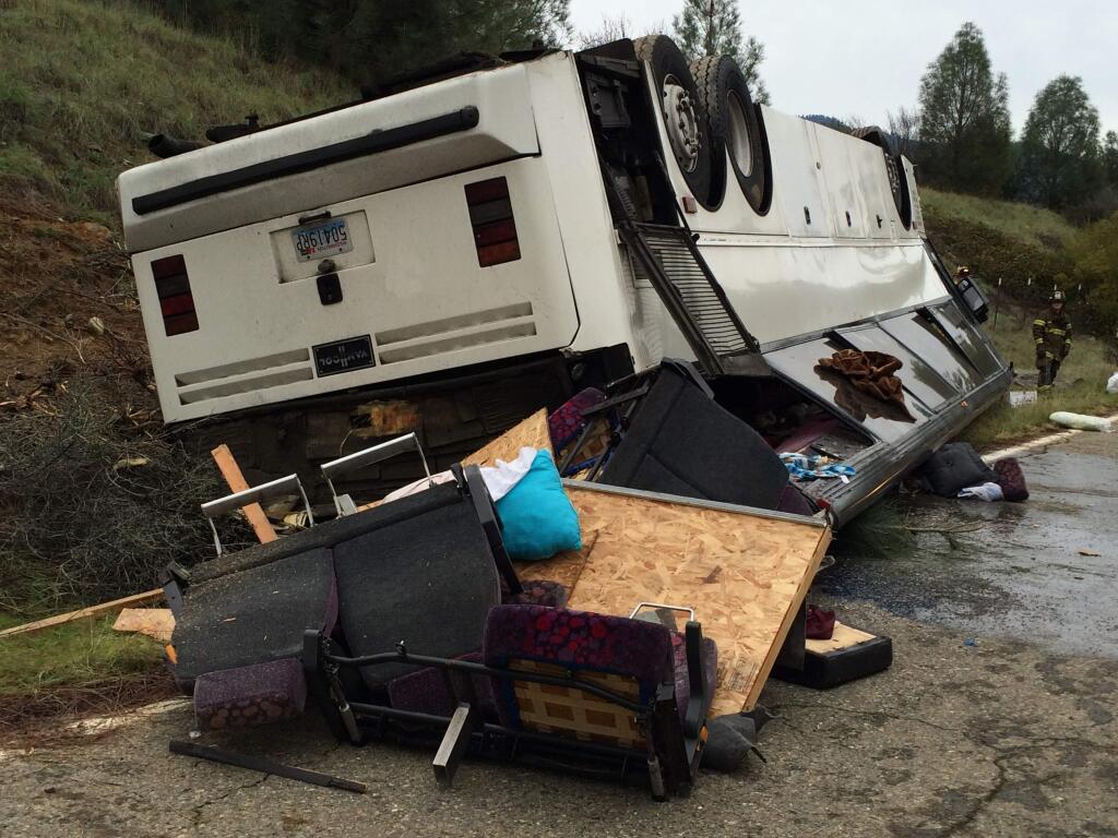 Emergency personnel check a tour bus that had already crashed earlier in the day overturned just off Interstate 5 in Northern California, killing one person and sending dozens to hospitals near the Pollard Flat area in Redding, Calif., Sunday, Nov. 23, 2014. The bus, bound from Los Angeles to Washington, crashed on Interstate 5 north of Lake Shasta on Sunday morning. (AP Photo/The Record Searchlight, Alayna Shulman)