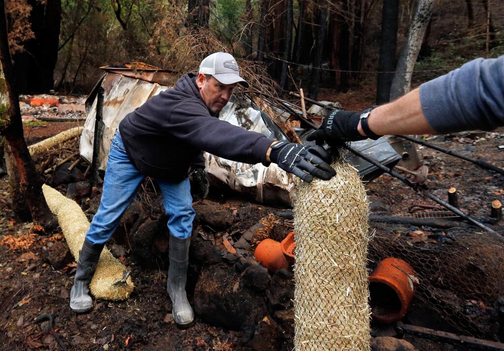 Todd O'Donnell, left, takes the end of a straw wattle from Bruce Hall, placing the erosion control features around the debris of a burned home along Adobe Canyon Road in Kenwood, California on Saturday, November 25, 2017. Volunteers with the Sonoma Ecology Center install sandbags and straw wattles for erosion control in strategic areas along Adobe Canyon Road to help keep toxins from fire ash out of the valley's waterways. (Alvin Jornada / The Press Democrat)