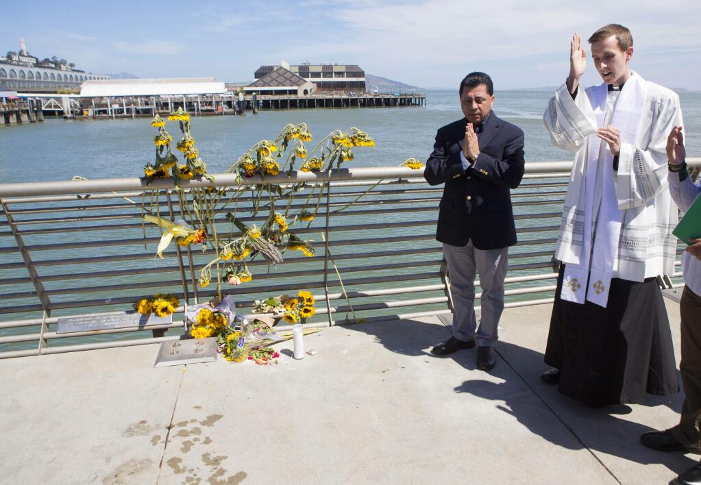 FILE - In this July 6, 2015 file photo, Father Cameron Faller, right, and Julio Escobar, of Restorative Justice Ministry, conduct a vigil for Kathryn Steinle on Pier 14 in San Francisco. (AP Photo/Beck Diefenbach, File)